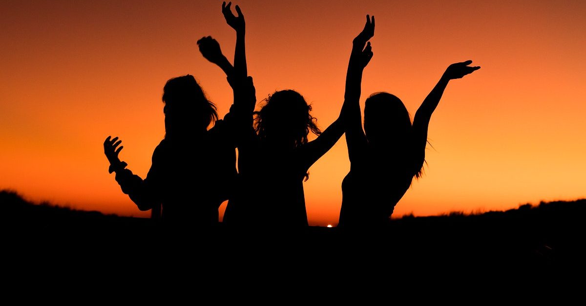 Silhouette of a group of friends celebrating in an orange sunset. Original public domain image from Wikimedia Commons